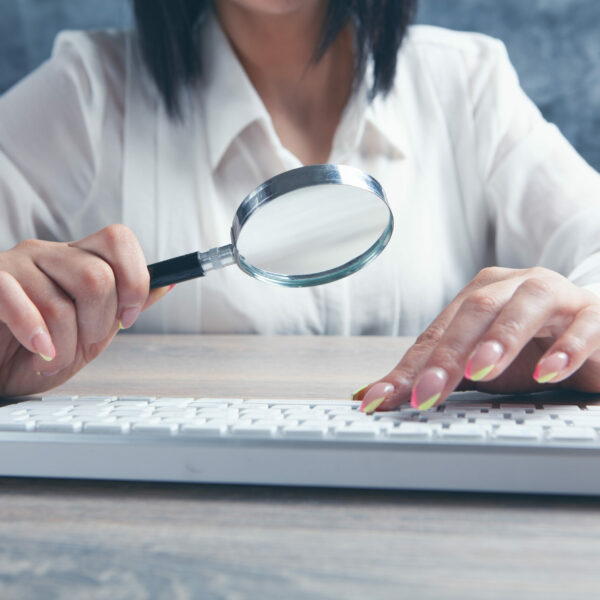 woman looking at the keyboard with a magnifying glass woman looking at the keyboard with a magnifying glass