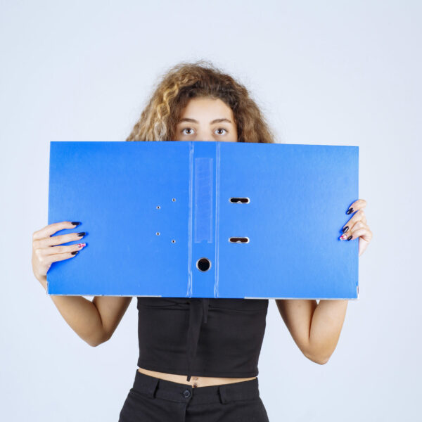 Blondie girl hiding her face behind a blue folder Blondie girl hiding her face behind a blue folder. High quality photo